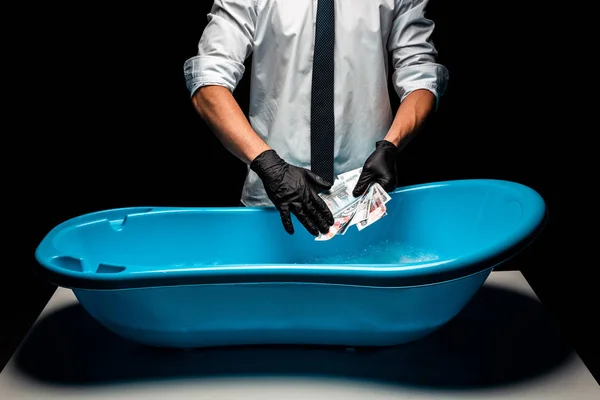Обрезанный вид человека в костюме, держащего российские деньги возле синего пластикового бассейна на черном — стоковое фото