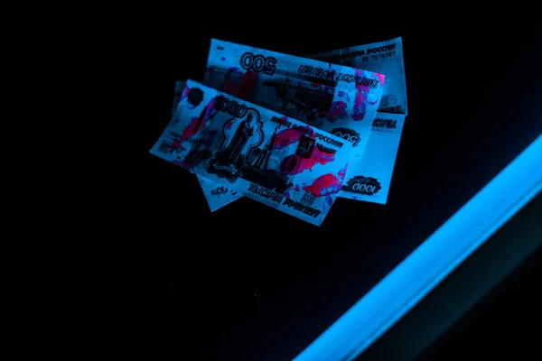 Blue ultraviolet lightning on russian money on black — Stock Photo