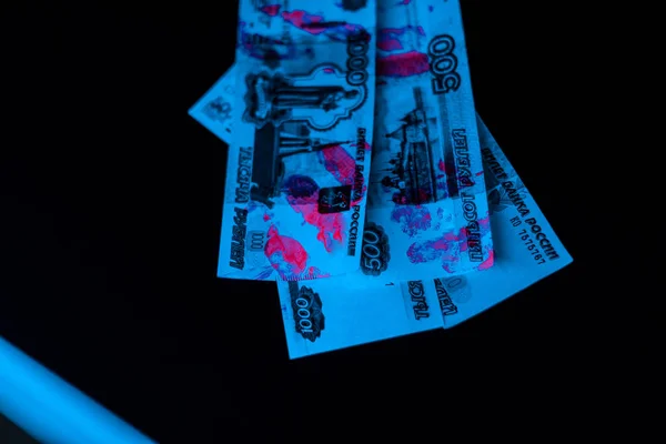 Selective focus of ultraviolet lightning on russian money on black — Stock Photo