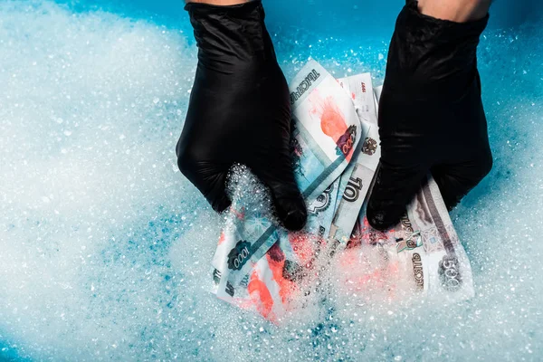 Вид зверху на людину в чорних гумових рукавичках, що миють російські гроші в мильних бульбашках з водою — стокове фото