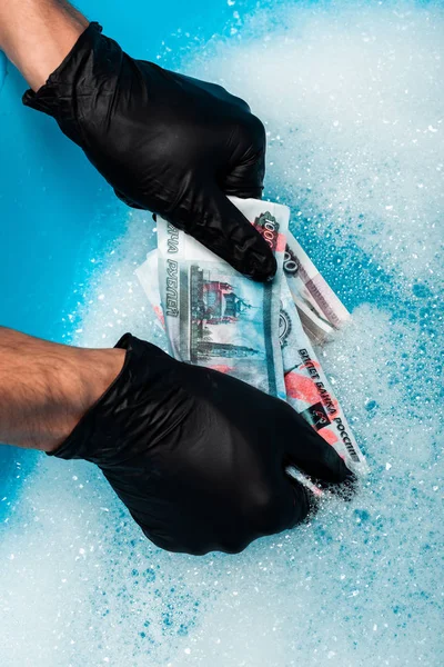 Overhead view of man in black rubber gloves washing russian money in soap bubbles — Stock Photo