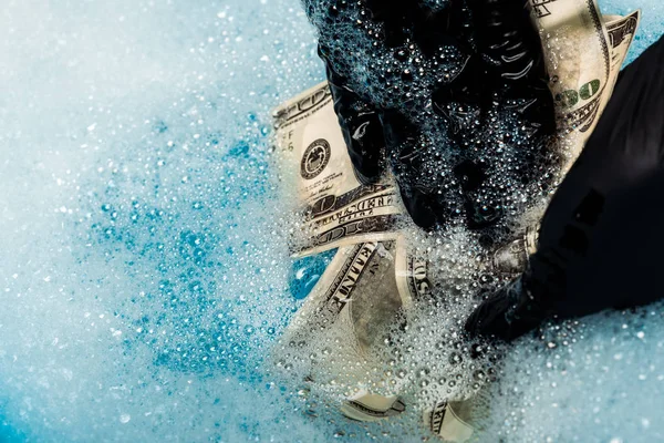 Close up de homem em luvas de borracha lavar notas de dólar em bolhas de sabão com água — Fotografia de Stock