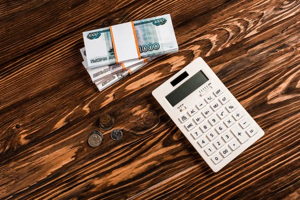 Vista aérea de la calculadora blanca cerca del dinero ruso en la mesa de madera - foto de stock