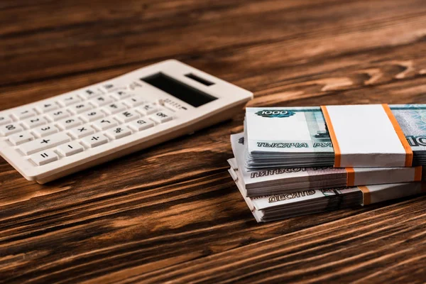 Selective focus of white calculator near russian money on wooden table — Stock Photo