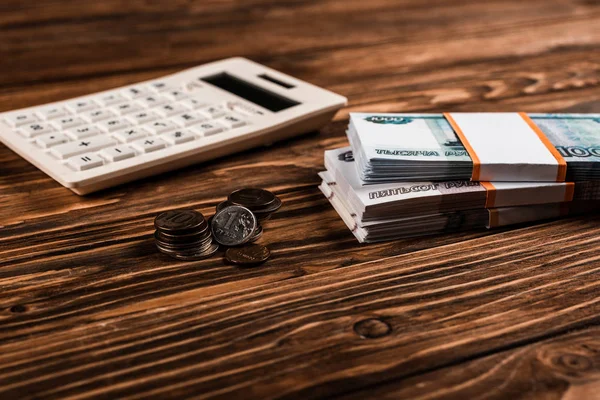 Селективный фокус белого калькулятора рядом с российскими деньгами и монетами на деревянном столе — стоковое фото