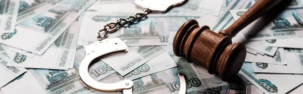 Panoramic shot of wooden gavel near handcuffs on russian money — Stock Photo