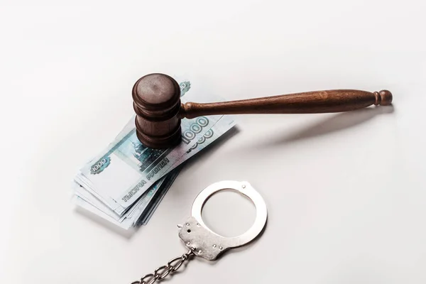 Вид зверху дерев'яного дарувальника біля наручників і російських грошей на білому — стокове фото