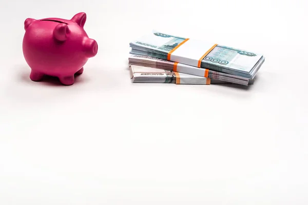Pink piggy bank near stacks of russian money on white — Stock Photo
