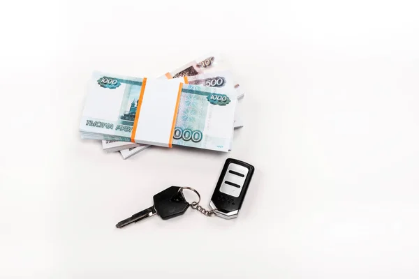 Вид на ключ автомобіля з ключовою ланцюга біля штабеля російських грошей на білому — стокове фото