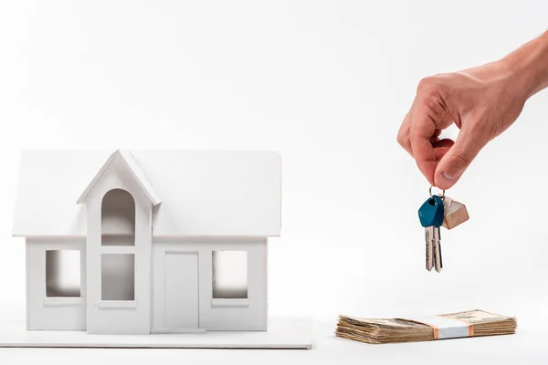 Vista cortada do homem segurando chaves perto da casa da caixa e dinheiro no branco — Fotografia de Stock