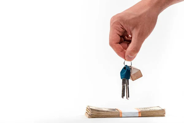 Cropped view of man holding keys near dollar banknotes isolated on white — Stock Photo