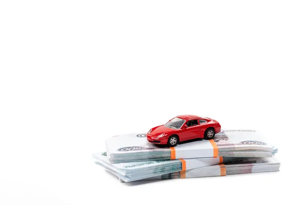 Червоний іграшковий автомобіль на стосах російських грошей ізольований на білому — стокове фото