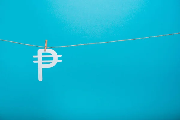 Wooden cloth pin on line rope near russian money sign on blue — стокове фото