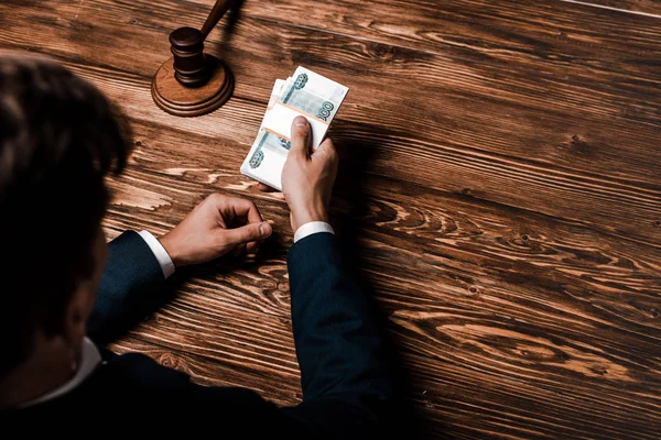 Overhead view of judge holding money near wooden gavel — Stock Photo