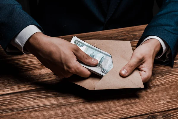 Cropped view of man holding envelope with russian money — Stock Photo