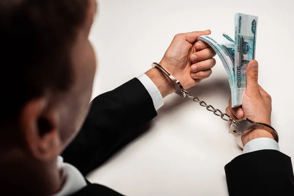 Вибірковий фокус бізнесмена в наручниках, що тримає хабар на білому — стокове фото