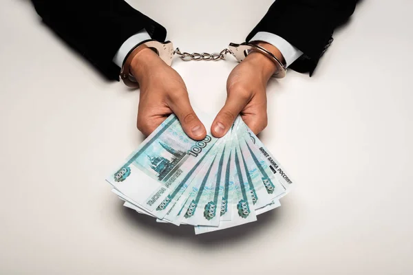 Top view of businessman in handcuffs holding russian money on white — Stock Photo