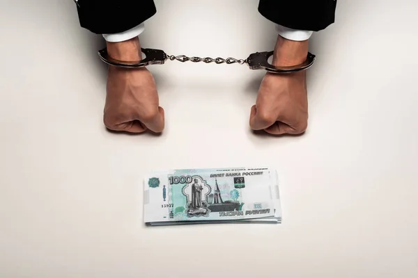 Вид бизнесмена в наручниках рядом с российскими деньгами на белом — стоковое фото