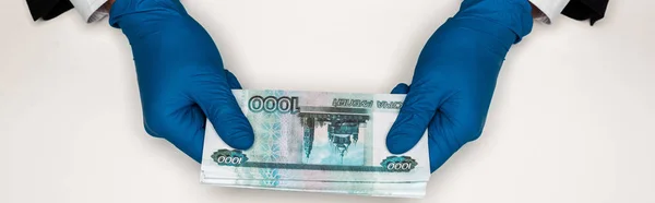 Plan panoramique de l'homme en gants de latex bleu tenant de l'argent russe sur blanc — Photo de stock