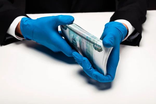 Recortado vista de hombre en guantes de látex celebración de dinero ruso en blanco - foto de stock