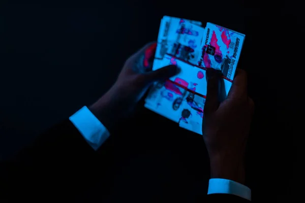 Обрізаний вид людини тримає російські гроші під ультрафіолетовим освітленням ізольований на чорному — стокове фото
