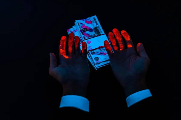 Cropped view of man near russian money under uv lighting isolated on black — Stock Photo