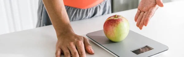 Foto panorámica de la mujer haciendo gestos cerca de escamas de alimentos y manzana - foto de stock