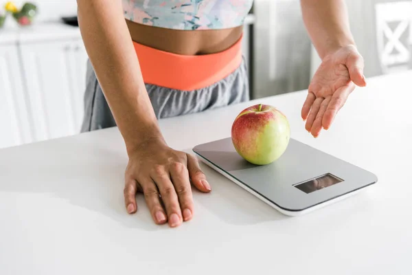 Обрезанный вид женщины жест рядом с пищевыми весами и яблоком — стоковое фото