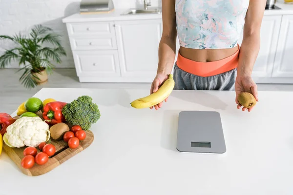 Vista cortada de mulher segurando frutas nas mãos perto de vegetais orgânicos — Fotografia de Stock