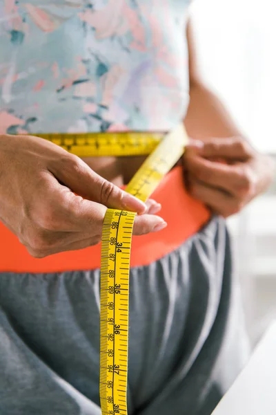 Selective focus of of sportive woman measuring waist — Stock Photo