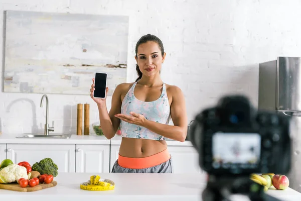 Selective focus of happy sportswoman holding smartphone with blank screen — Stock Photo