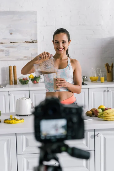 Selective focus of happy video blogger pouring smoothie into glass — Stock Photo