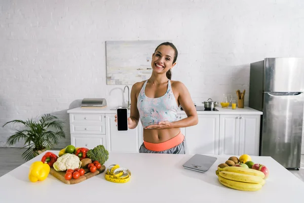 Feliz esportista gestos perto de smartphone com tela em branco — Fotografia de Stock