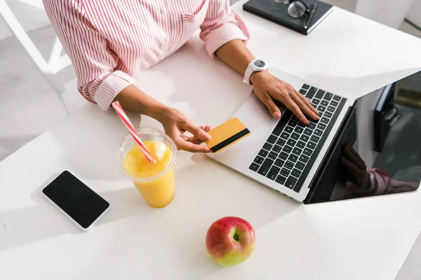 Ansicht der Frau mit Kreditkarte in der Nähe von Laptop und Smartphone mit leeren Bildschirmen — Stockfoto