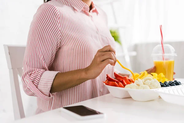 Cropped view of woman holding fork near food container with vegetables — Stock Photo