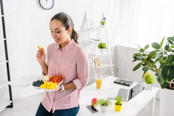 Heureuse fille tenant fourchette en plastique près des légumes dans le récipient alimentaire — Photo de stock