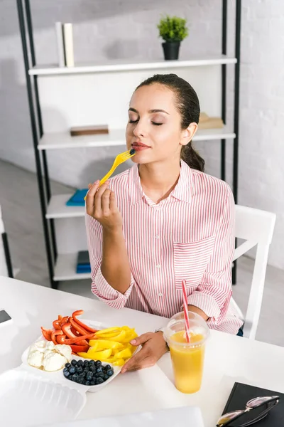 Femme attrayante avec les yeux fermés tenant fourchette en plastique avec paprika — Photo de stock
