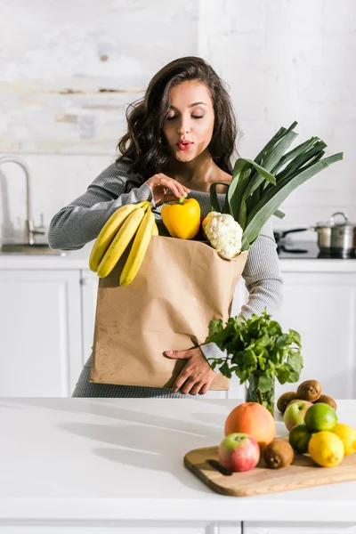 Jolie femme debout près du sac en papier avec de la nourriture savoureuse — Photo de stock