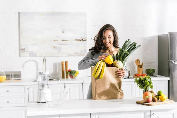 Femme heureuse debout près du sac en papier avec de la nourriture savoureuse — Photo de stock