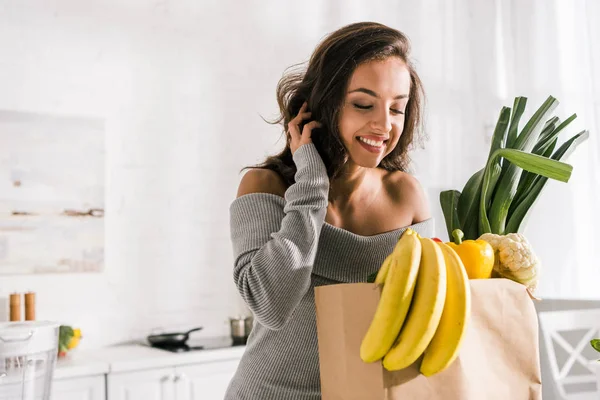 Happy girl looking at groceries in paper bag — Stock Photo