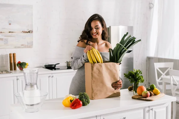 Smiling woman standing near paper bag with tasty food — Stock Photo