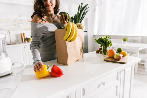 Vista ritagliata della donna in piedi vicino generi alimentari in cucina — Foto stock