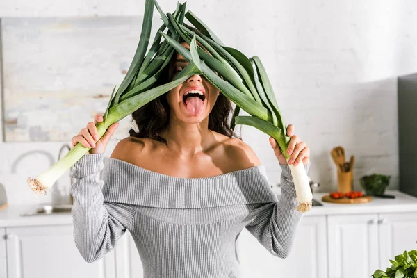 Mujer feliz mostrando lengua mientras sostiene puerro - foto de stock