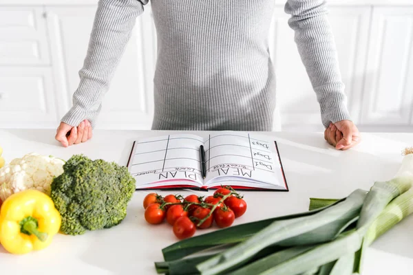 Cropped view of woman standing with clenched fists near vegetables — Stock Photo