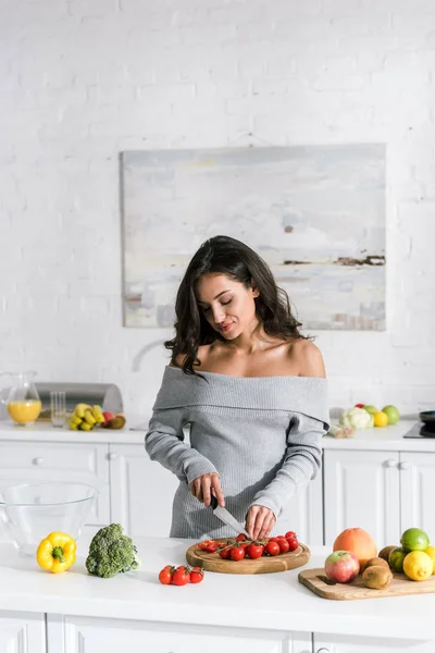 Приваблива дівчина тримає ніж біля смачних вишневих помідорів — стокове фото