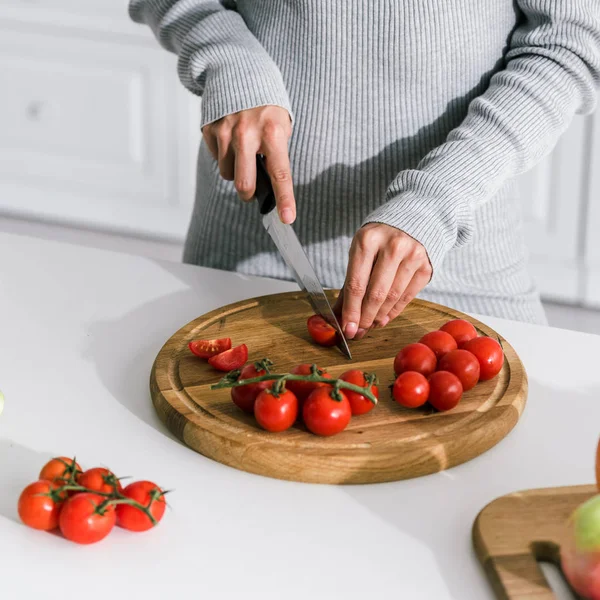 Vista cortada de menina cortando tomates cereja vermelhos — Fotografia de Stock