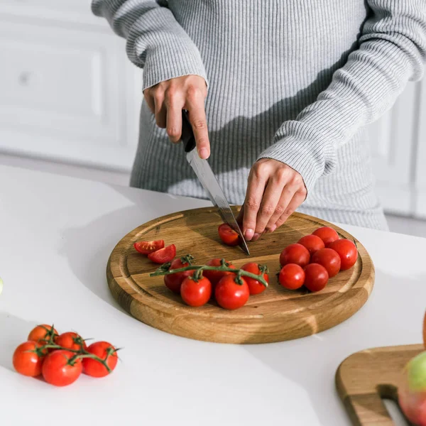 Abgeschnittene Ansicht eines Mädchens, das rote Kirschtomaten schneidet — Stockfoto