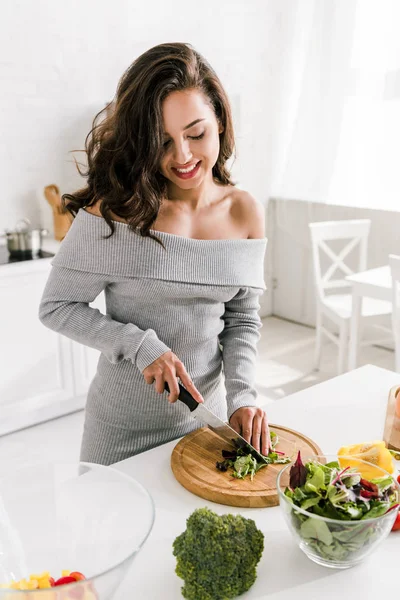Selective focus of happy girl cutting broccoli on chopping board — Stock Photo