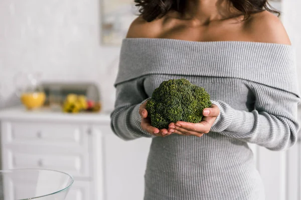 Vista recortada de la mujer joven sosteniendo brócoli verde - foto de stock