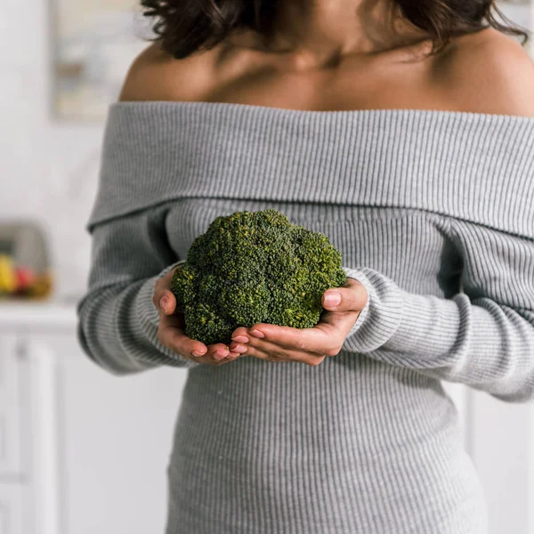 Vista recortada de la mujer joven sosteniendo brócoli verde y fresco - foto de stock